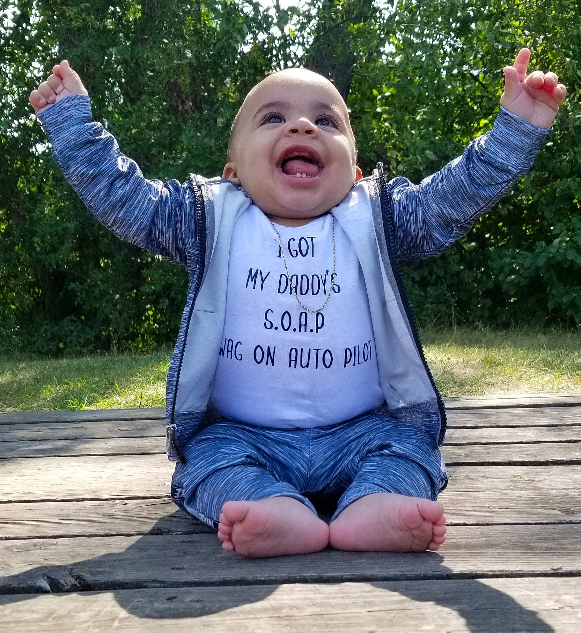 Markeese is registered to the contest to win money with this photo: child, cool, face, facial_expression, fun, grass, hand, happy, head, joint, leg, outerwear, people, person, public_space, sitting, smile, summer, t_shirt, toddler
