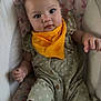 adorable, baby, child, closeup, comfort, cushion, cute, expression, fabric, floral_pattern, indoor, infant, looking_at_camera, portrait, romper, seated, small_hands, soft_lighting, yellow_bib, young_child