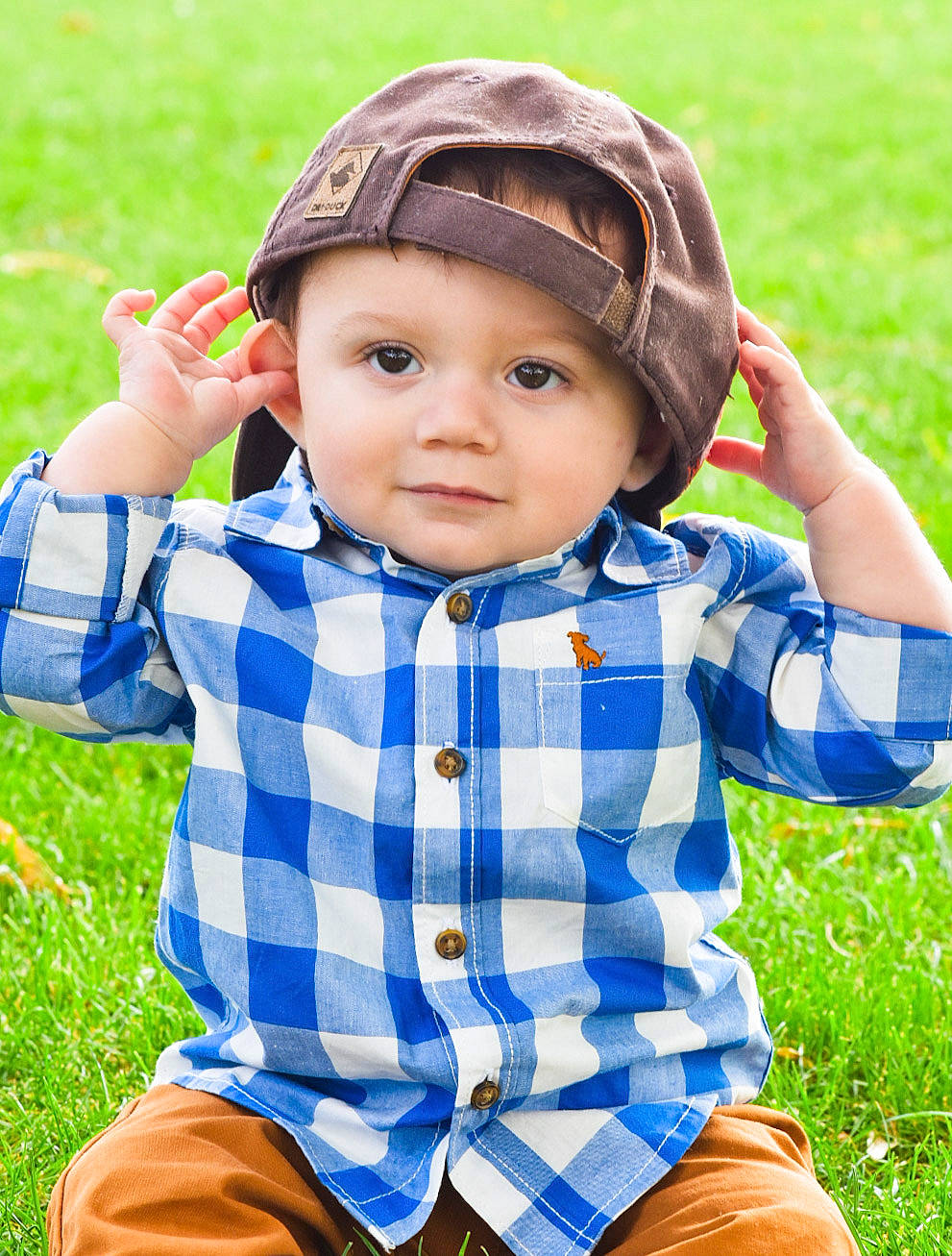 Michael is registered to the contest to win money with this photo: baby, cheek, child, fashion_accessory, finger, grass, hand, happy, head, headgear, headwear, meadow, mouth, nose, people_in_nature, person, plant, play, sitting, smile