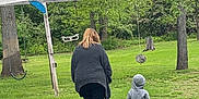 Lukas joined the competition — help win amazing prizes! casual, child, cup, daytime, grass, greenery, hoodie, nature, outdoor, pants, park, playground, recreation, relaxation, shoes, swing, table, trees, walking, woman