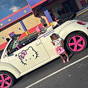 Legend joined the competition — help win amazing prizes! child, girl, car, convertible, hello_kitty, pink, rainbow, parking_lot, building, sign, smiling, outdoor, sunny, fashion, accessory, toy, vehicle, person, colorful, happy