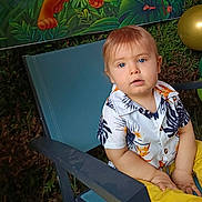 Julio a rejoint le concours — aidez-le/la à gagner de superbes lots ! background, balloons, blue_eyes, casual_clothing, chair, child, cute, decorations, face, greenery, holiday, outdoor, party, person, portrait, shirt, sitting, summer, toddler, yellow_pants