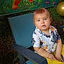 background, balloons, blue_eyes, casual_clothing, chair, child, cute, decorations, face, greenery, holiday, outdoor, party, person, portrait, shirt, sitting, summer, toddler, yellow_pants