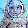 baby, child, blue_eyes, knit_hat, bear_ears, pacifier, fuzzy_onesie, winter_clothing, cute, portrait, cold_weather, outdoor, soft_texture, infant, face, warm, clothing, person, closeup, adorable