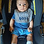 Zayden is registered to the contest to win money with this photo: baby, car_seat, bib, blue_clothing, socks, infant, child, indoor, wooden_floor, warning_label, person, cute, portrait, seat, young_child, expression, sitting, small_hands, footwear, closeup