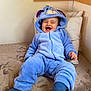 Soeïny participe au concours pour gagner de l'argent avec cette photo : baby, child, blue_onesie, costume, eeyore, smiling, laughing, couch, pillow, indoor, cozy, soft_fabric, socks, happy, cute, person, infant, seated, plush, hooded_outfit