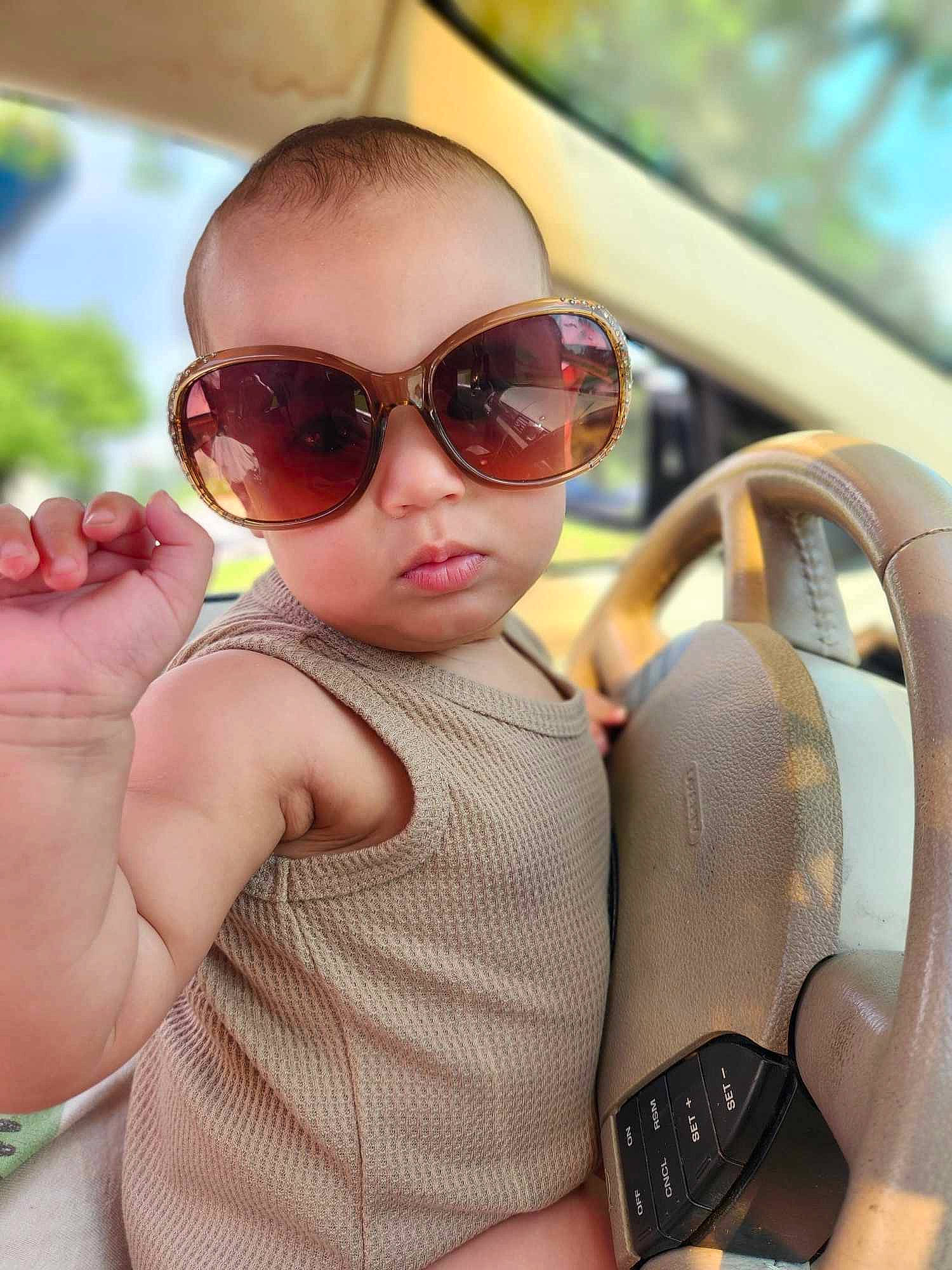 Serenity is registered to the contest to win money with this photo: arm, automotive_mirror, baby, cool, eyewear, facial_expression, finger, glasses, goggles, hand, happy, leisure, lip, motor_vehicle, mouth, person, skin, steering_wheel, sunglasses, toddler