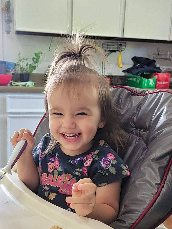 Maxine is registered to the contest to win money with this photo: auto_part, blond, child, comfort, eye, facial_expression, finger, fun, hairstyle, happy, head, joy, leisure, person, plate, product, sitting, skin, smile, table