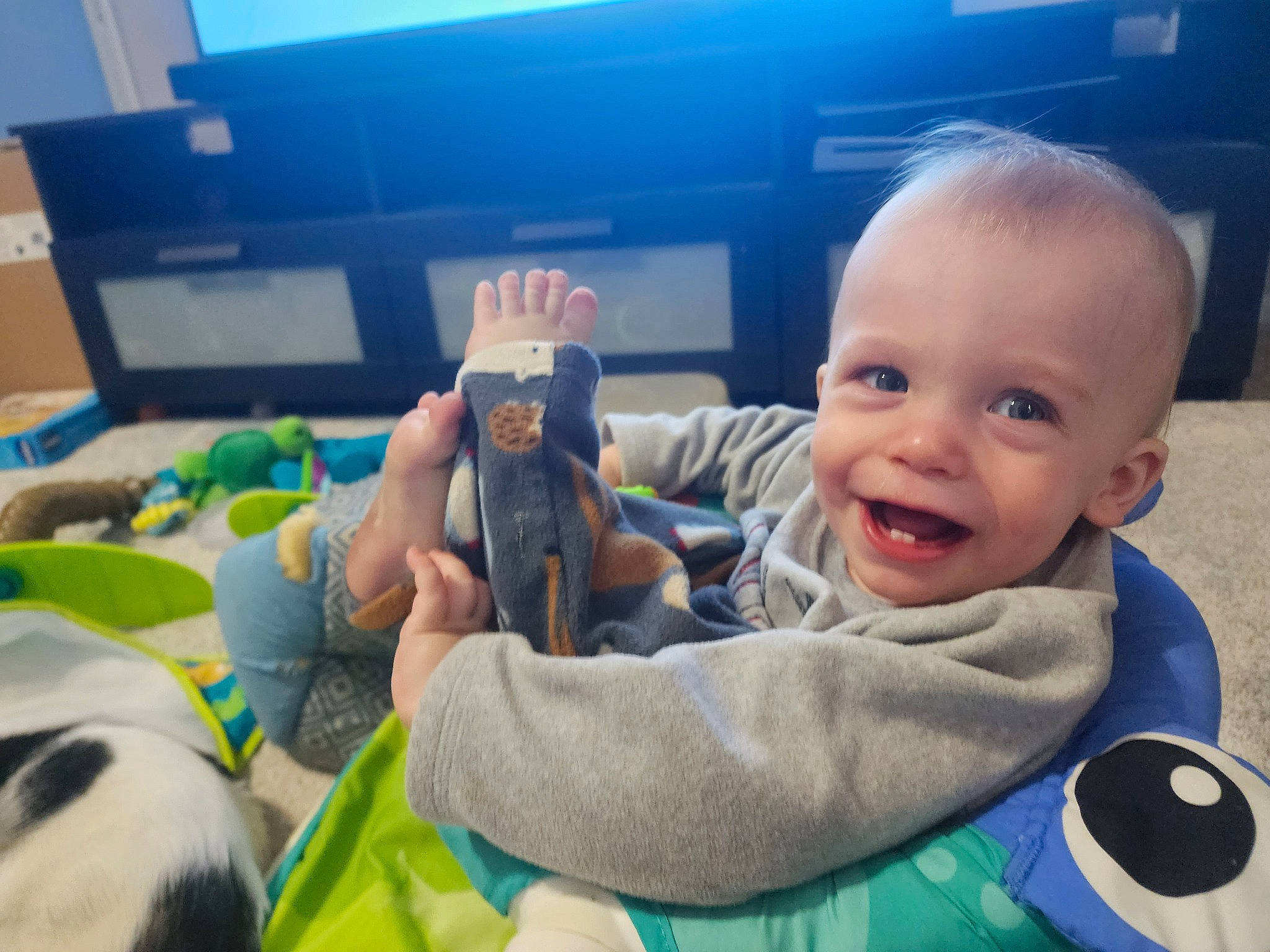 Walker is registered to the contest to win money with this photo: baby, child, finger, fun, gesture, grass, happy, human_body, laugh, leisure, person, play, recreation, sitting, smile, stuffed_toy, t_shirt, tableware, thumb, toddler