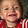baby, child, smiling, face, blue_eyes, teeth, necklace, red_shirt, striped_clothing, portrait, happy, infant, cute, closeup, person, indoors, background, head, skin, expression