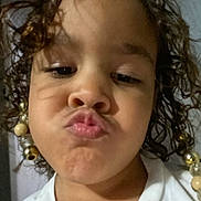 Bella joined the competition — help win amazing prizes! child, face, selfie, curly_hair, beads, puckered_lips, indoor, white_shirt, closeup, expression, person, portrait, cute, youth, head, skin, hair, accessory, smile, playful