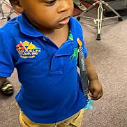 Jahmir joined the competition — help win amazing prizes! black_hat, black_shoes, blue_polo_shirt, braided_hair, carpet, child, clothing, drum_set, floor, indoor, musical_instrument, pacifier_clip, person, serious_expression, standing, stool, tan_pants, toddler, toy, young_child