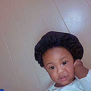 Jahmir is registered to the contest to win money with this photo: toddler, child, face, bonnet, white_clothing, indoors, wall, curious, portrait, person, young_child, sitting, hand, expression, brown_skin, headwear, casual, room, cute, baby