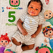 Tylan is registered to the contest to win money with this photo: 5_months, baby, cartoon_characters, celebration, child, cocomelon, colorful, cross_necklace, cute, happy, indoors, infant, lying_down, musical_notes, playful, portrait, smiling, soft_texture, striped_clothing, white_blanket
