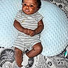 baby, infant, child, pillow, striped_clothing, socks, gold_necklace, carpet, patterned_rug, indoor, cute, lying_down, comfortable, texture, small_child, portrait, person, home, relaxing, adorable