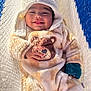 baby, child, smiling, tongue_out, hooded_clothing, bear_design, onesie, hammock, knit_texture, sunlight, shadow, cozy, cute, infant, happy, outdoor, soft_clothing, portrait, relaxed, playful