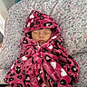 baby, sleeping, blanket, hooded, pink, leopard_print, heart_pattern, pillow, floral, patterned, cozy, resting, infant, cute, soft, fabric, indoors, child, peaceful, portrait