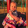 Mia joined the competition — help win amazing prizes! baby, blanket, playground, swing, child, outdoor, sunlight, rope, park, woodchips, red_pole, clothing, reaching_hand, daylight, nature, greenery, happy, cute, infant, play