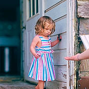 Bray joined the competition — help win amazing prizes! child, toddler, barefoot, striped_dress, curly_hair, door, wooden_porch, hand, exploring, outdoor, building, wall, old_wood, summer, daylight, person, young_child, curious, standing, playful