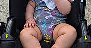Vianney joined the competition — help win amazing prizes! baby, infant, child, stroller, sitting, smiling, portrait, outdoor, pavement, canopy, harness, floral_clothing, bib, bare_feet, toes, black_hair, face, safety_labels, happy, photography