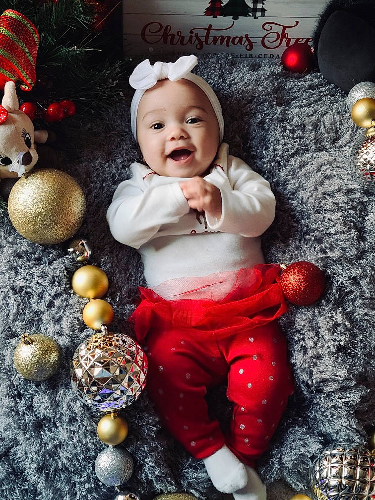 Toni is registered to the contest to win money with this photo: baby, baby_toddler_clothing, child, christmas, christmas_decoration, christmas_eve, christmas_ornament, costume_hat, doll, event, fictional_character, flash_photography, happy, headwear, lighting, ornament, person, red, smile, toddler