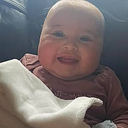 Gracie-May is registered to the contest to win money with this photo: baby, smiling, blanket, couch, leather, indoor, child, happy, face, infant, comfort, soft_toy, natural_light, portrait, cozy, clothing, sitting, cute, young_child, home