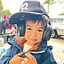 Jayden Reyes is registered to the contest to win money with this photo: background, boy, cap, casual, child, cute, daylight, expression, face, fashion, hat, headphones, jacket, outdoor, person, portrait, smile, street, winter_clothing, young