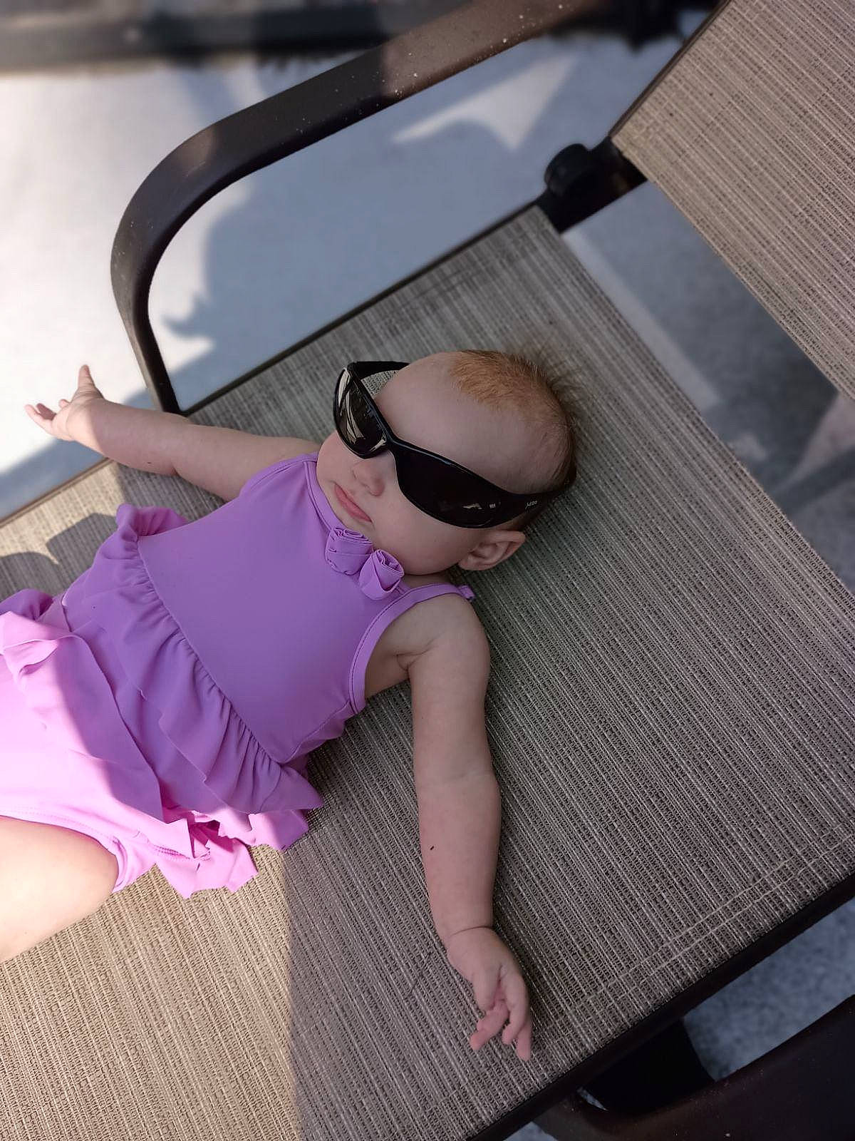 Zara is registered to the contest to win money with this photo: baby, baby_toddler_clothing, child, comfort, eyewear, flooring, foot, fun, glasses, goggles, leisure, magenta, person, personal_protective_equipment, purple, sitting, sleeve, sunglasses, thigh, toddler