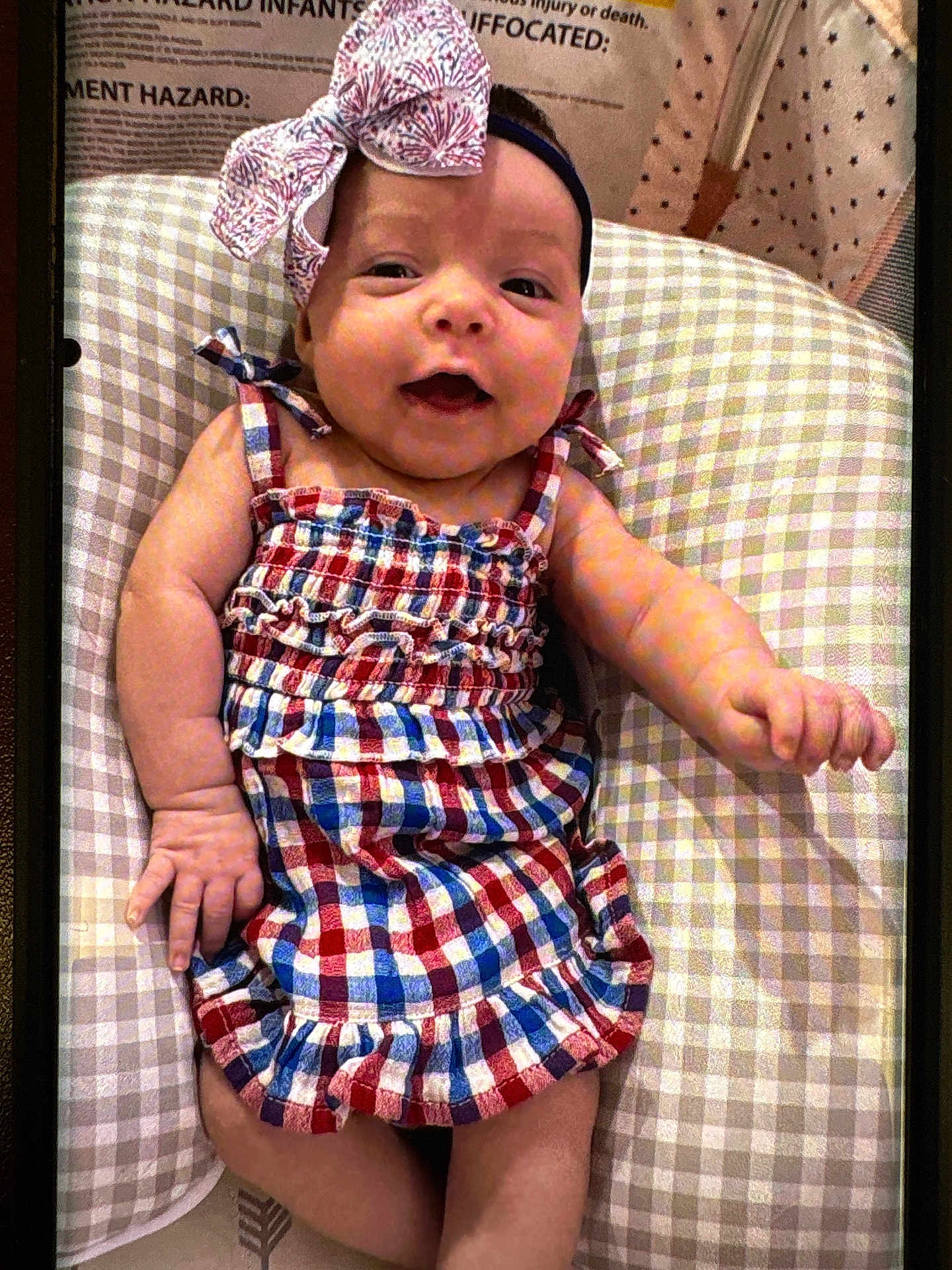 Delilah P. joined the competition — help win amazing prizes! baby, infant, smiling, dress, headband, bow, cushion, checked_pattern, happy, child, cute, portrait, indoors, young, skin, person, clothing, baby_girl, resting, closeup