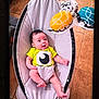 baby, infant, baby_swing, yellow_shirt, toy, colorful_toys, floor, tile_floor, indoor, cute, child, playtime, happy, person, small_person, home, relaxing, seat, smiling, looking_up