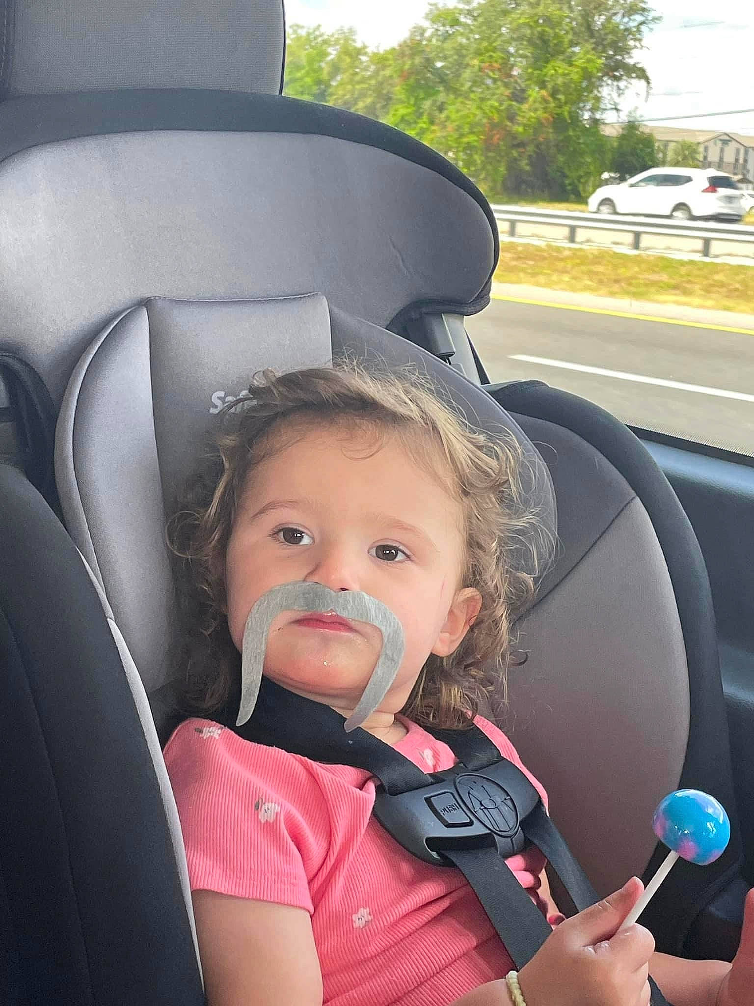 Thea is registered to the contest to win money with this photo: auto_part, automotive_design, automotive_exterior, car, car_seat, car_seat_cover, eye, face, facial_expression, head, microphone, motor_vehicle, person, plant, steering_wheel, toddler, tree, vehicle, vehicle_door, wheel