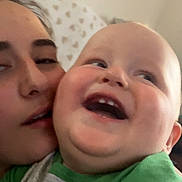 Willie is registered to the contest to win money with this photo: baby, infant, adult, face, portrait, selfie, smiling, laughing, happy, cheek_to_cheek, indoor, close_up, green_shirt, pillow, bedroom, soft_lighting, family, parent, candid, photography