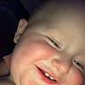 Willie is registered to the contest to win money with this photo: child, smiling, portrait, close_up, face, eyes, nose, mouth, teeth, skin, head, indoor, dim_lighting, blurred_background, lying_down, happy, young_person, photography, vertical_image, cozy