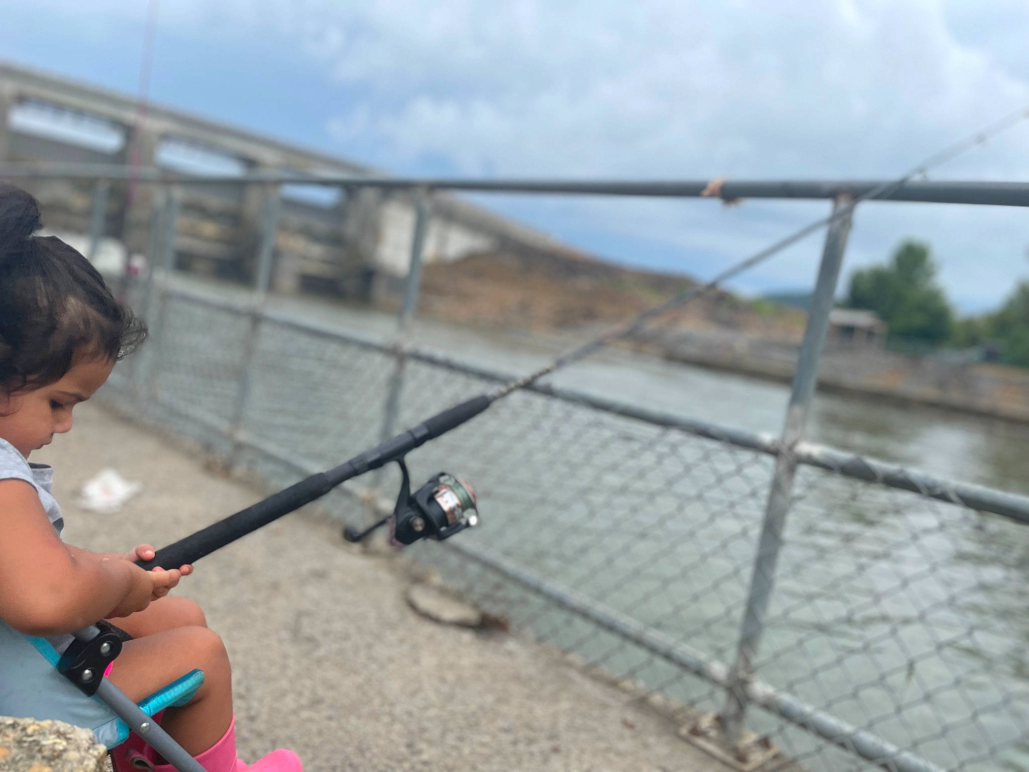 Alessandra is registered to the contest to win money with this photo: angling, bridge, casting_fishing, chain_link_fencing, cloud, fence, fishing_rod, guard_rail, handrail, landscape, leisure, mesh, person, recreation, reservoir, sky, toddler, travel, vacation, water