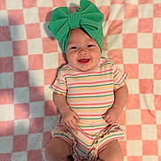 Avalyn joined the competition — help win amazing prizes! baby, smiling, headband, green_bow, striped_clothing, onesie, blanket, checkered_pattern, pink, white, infant, cute, happy, lying_down, child, portrait, indoors, soft_texture, colorful, hands