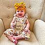 baby, child, smiling, headband, yellow_bow, floral_outfit, armchair, beige, wooden_sign, five_months, happy, sitting, cute, infant, portrait, indoors, texture, person, feet, hand