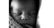 River is registered to the contest to win money with this photo: baby, newborn, sleeping, black_and_white, close_up, face, infant, wrapped, blanket, hand, peaceful, soft_lighting, portrait, cute, tiny_fingers, resting, calm, texture, monochrome, indoors