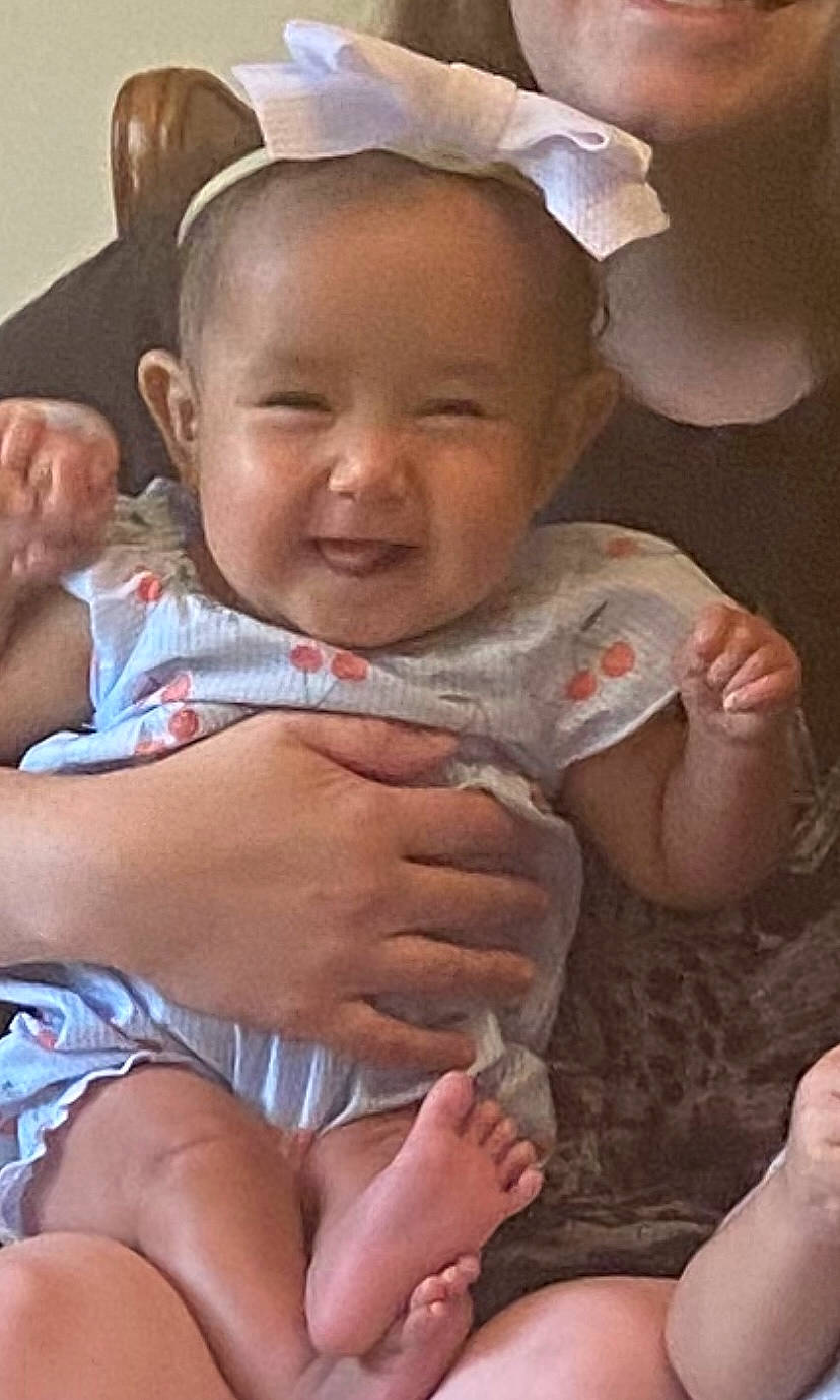 Emily is registered to the contest to win money with this photo: baby, baby_toddler_clothing, cheek, child, eye, facial_expression, finger, fun, gesture, hand, happy, head, human_body, lip, mouth, person, pink, skin, smile, thumb