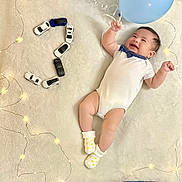 Elian Sebastian is registered to the contest to win money with this photo: baby, balloons, birthday, blanket, blue, celebration, child, cute, decorations, happy, indoor, infant, lights, number_two, playful, polka_dot_socks, smiling, soft_texture, toy_cars, white_onesie