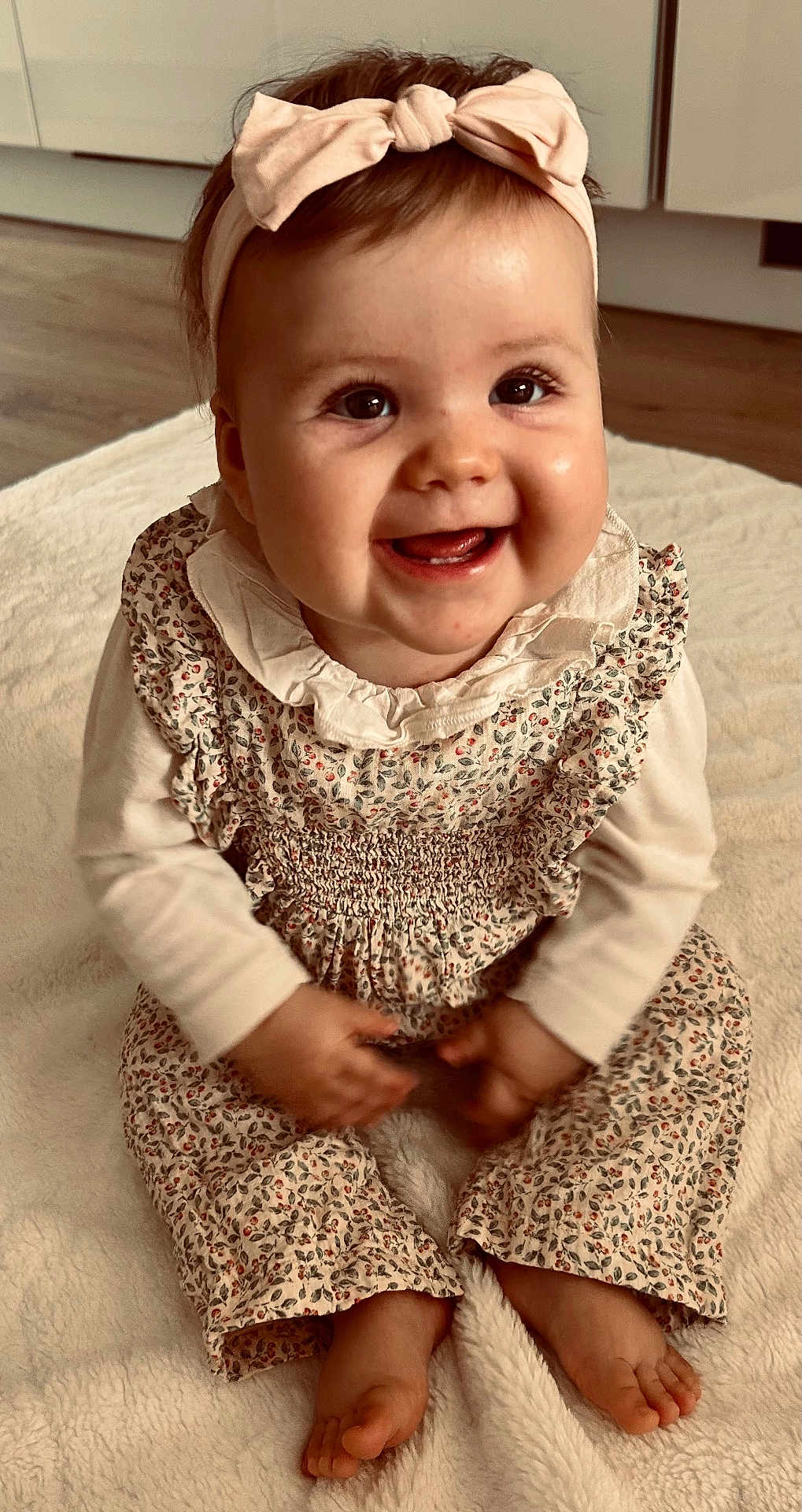 Louise a rejoint le concours — aidez-le/la à gagner de superbes lots ! baby, child, smiling, happy, headband, bow, floral_outfit, sitting, barefoot, blanket, indoors, cute, portrait, infant, young_child, face, hands, feet, long_sleeve, floor