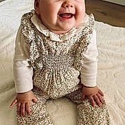 Louise participe au concours pour gagner de l'argent avec cette photo : baby, child, smiling, sitting, headband, bow, floral_outfit, long_sleeves, barefoot, blanket, indoor, happy, cute, infant, portrait, hands, feet, floor, wooden_floor, clothing