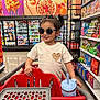 Isabella is registered to the contest to win money with this photo: child, shopping_cart, grocery_store, sunglasses, leopard_print, tshirt, heart_design, snacks, cereal, aisle, shopping, smiling, hair_tied, plastic_cup, straw, colorful, retail, store_shelves, young_child, indoor