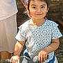 Isabella is registered to the contest to win money with this photo: child, girl, outdoor, toy, statue, animal_statue, pigtails, tattoo, adult, hand, smile, shorts, tshirt, footwear, brick_wall, window, sunlight, play, happy, person
