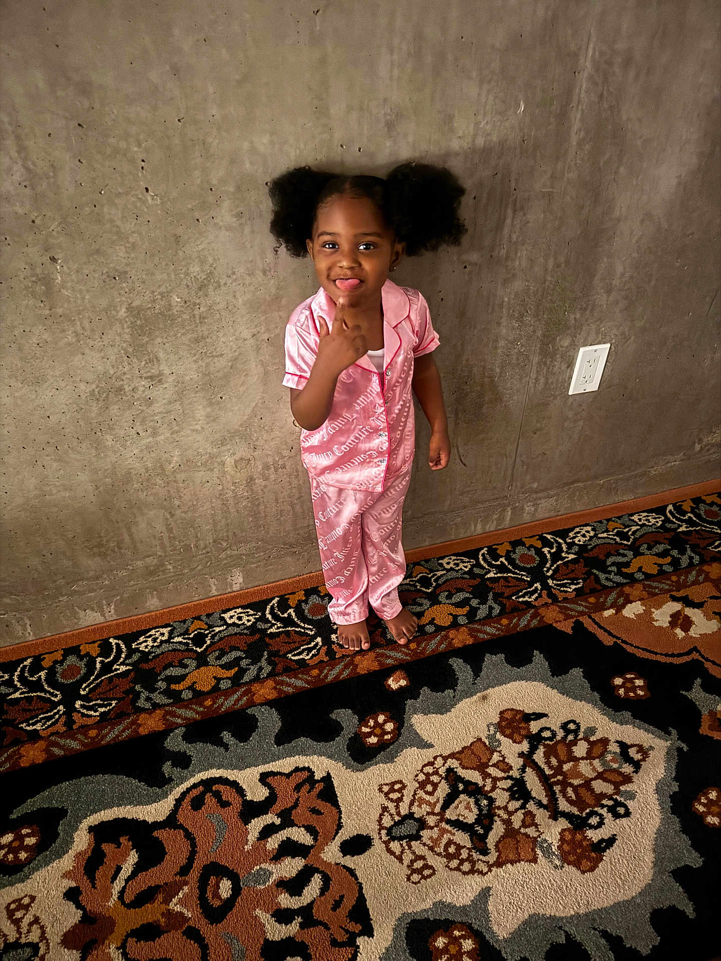 Covenant joined the competition — help win amazing prizes! child, girl, pajamas, pink, barefoot, carpet, patterned_rug, concrete_wall, indoor, playful, tongue_out, pointing, smiling, hair_puffs, person, floor, wall_socket, expression, cute, standing