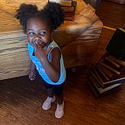 Covenant joined the competition — help win amazing prizes! child, girl, pigtails, smiling, indoor, wooden_floor, blue_shirt, black_shorts, pink_shoes, table, wooden_table, decorative_books, furniture, happy, playful, person, standing, cute, finger_in_mouth, room