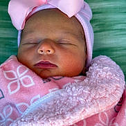 Magnolia is registered to the contest to win money with this photo: baby, infant, newborn, sleeping_baby, pink_bow, beanie, blanket, swaddle, close_up, portrait, face, closed_eyes, nose, lips, cheeks, soft_texture, fabric_pattern, green_background, adorable, peaceful