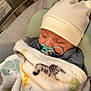 adorable, animal_print, baby, baby_seat, blanket, child, closeup, comfort, cozy, cute, hat, indoor, infant, nursery, pacifier, peaceful, resting, sleeping, soft_lighting, wearing_clothes