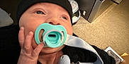 Dayton joined the competition — help win amazing prizes! baby, infant, pacifier, hat, black_clothing, hand, face, indoors, carpet, furniture, clip, curious, newborn, person, holding, closeup, looking_up, soft_lighting, home, cute