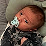 Dayton is registered to the contest to win money with this photo: baby, infant, pacifier, blanket, camo_clothing, pillow, soft_toy, hand, face, portrait, indoor, resting, cute, young_child, sleepwear, fist, head_support, cozy, child, newborn