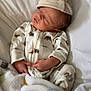 Dayton is registered to the contest to win money with this photo: newborn, baby, sleeping, onesie, hat, blanket, cushion, infant, clothing, cozy, resting, cute, soft, white, animal_print, peaceful, indoor, child, portrait, relaxing